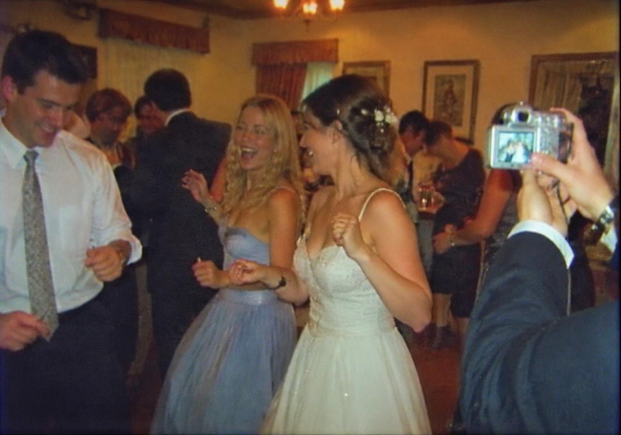 Guests dancing at a wedding while a friend films